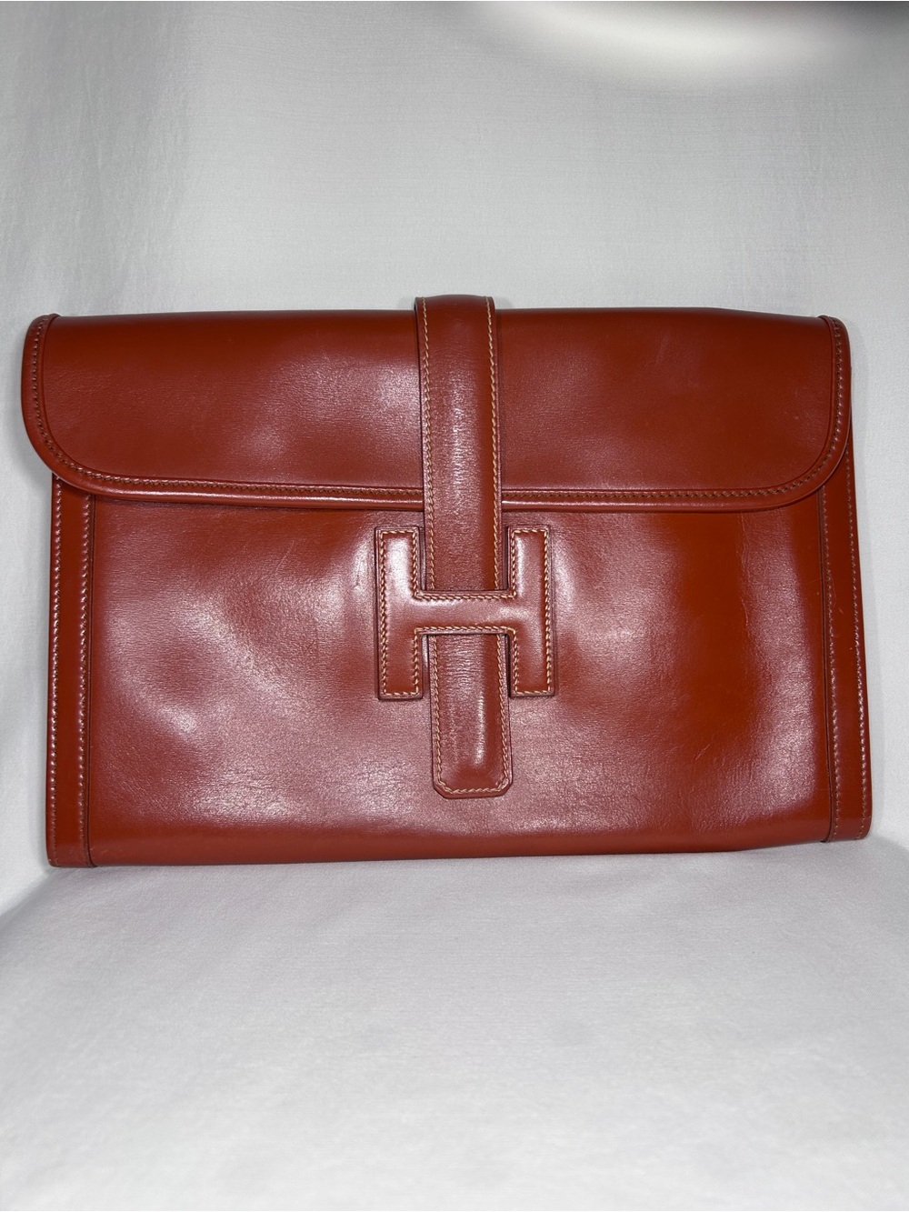 Hermès Jige clutch in a rich red-brown color crafted from Box calf leather